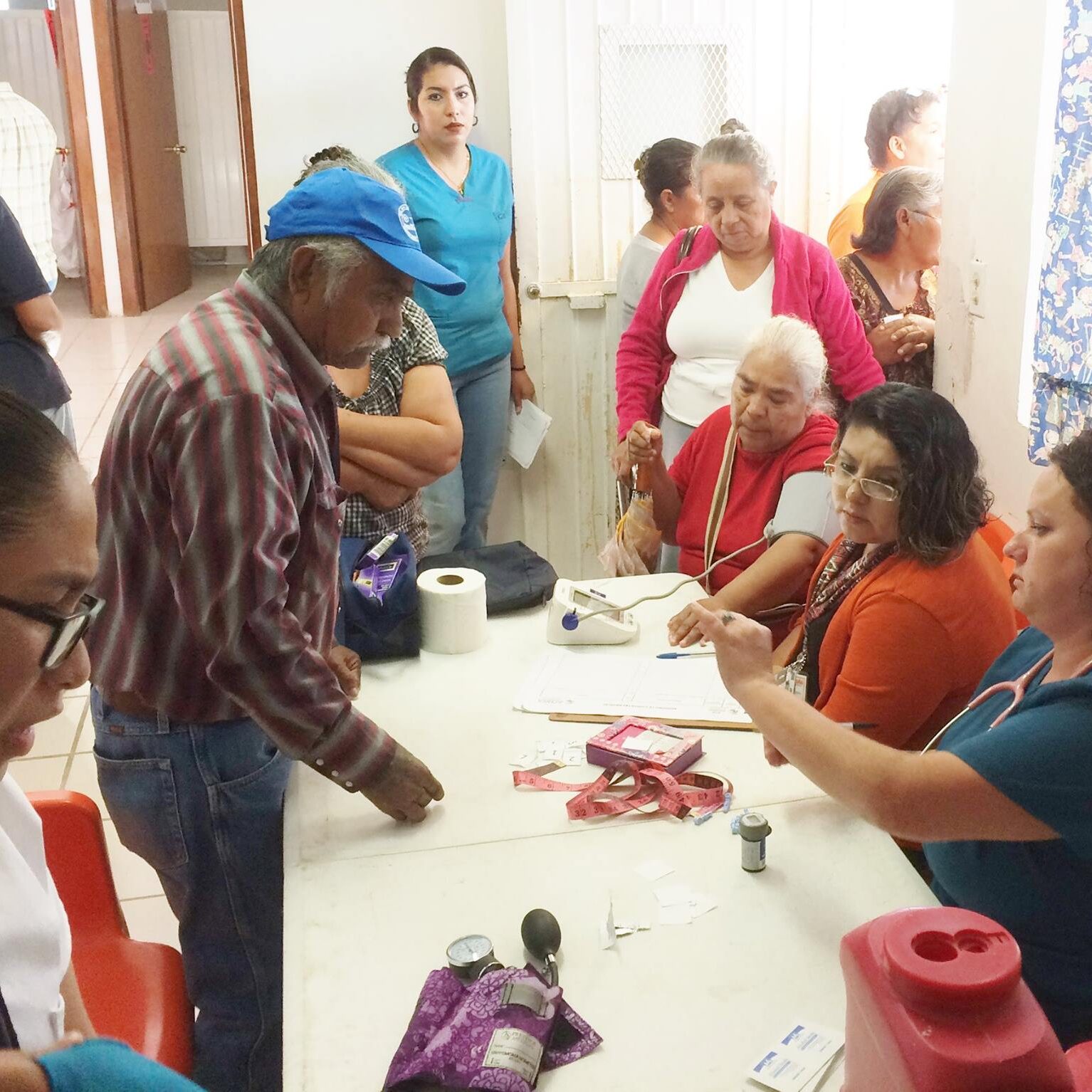 Intake area for clinic patients. AMO volunteer Devin testing patient's blood sugar. 